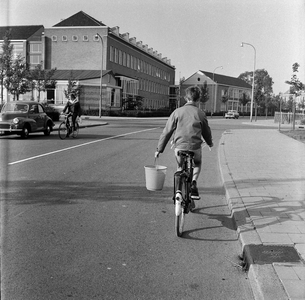 125626 Afbeelding van een fietsende jongen met een emmer in zijn hand op de Burgemeester Fockema Andreaelaan te ...